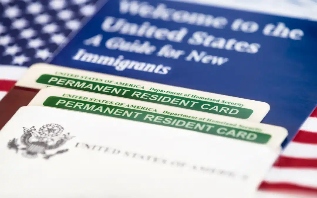 Permanent resident cards of the United States of America, green card, with the American flag in the background. Immigration concept. Closed with shallow depth of field.