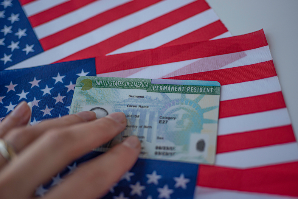 Permanent resident green card of the United States of America on the flag of the United States. Above view.